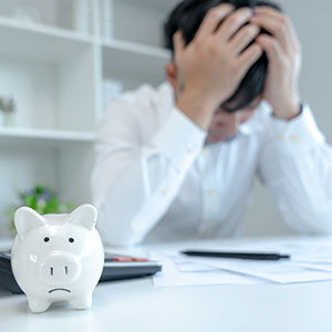 image of man with hands on his head and empty piggy bank
